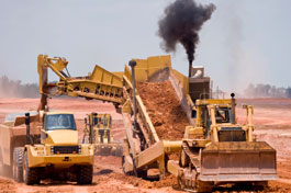 A photograph of a dirt scooper and loader putting dirt into a dumptruck at a construction site.